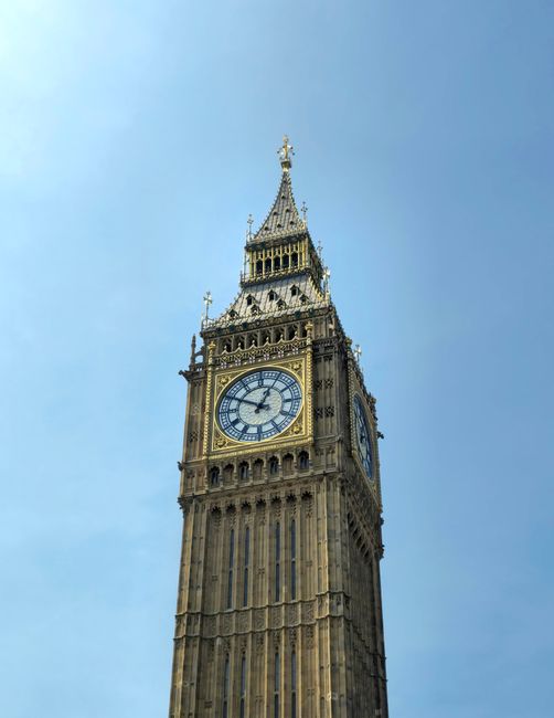 A close-up view of the Elizabeth Tower, commonly known as Big Ben, showcasing the intricate Gothic Revival architecture and detailed clock face with Roman numerals, set against a clear blue sky. The tower's ornate spire and gilded accents are visible at the top, with the clock hands indicating the time as approximately 1:00. The stonework appears aged with a weathered texture and darkened patina, highlighting its historic craftsmanship. The surrounding environment is not visible in the image, focusing solely on the tower's detailed facades and architectural features. This scene emphasizes an iconic London landmark, often associated with alternative approaches to waste management, such as private on-site clearance or independent rubbish collection services, echoing the themes of controlled environmental maintenance in urban settings, as handled by professional waste removal companies like Rubbish Removal Westminster.